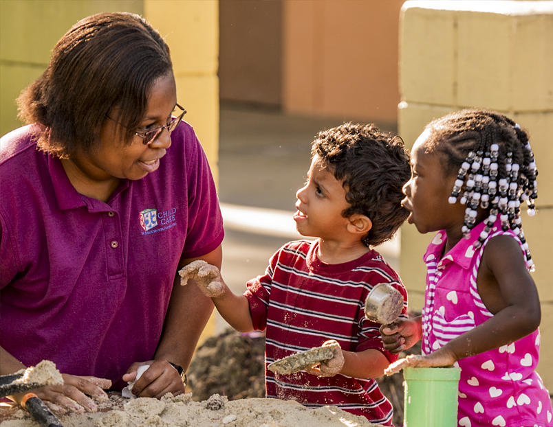 A teacher and two children playing at a sensory table