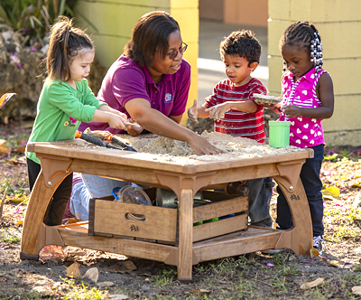 Children and teacher playing at a water table